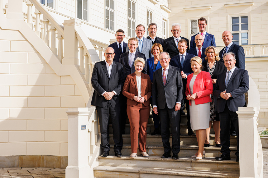 Männer und Frauen stehen vor einem alten Gebäude auf einem Treppenaufgang und posieren für ein Foto.