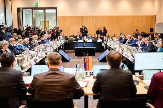 Männer und Frauen sitzen an einem Konferenztisch.