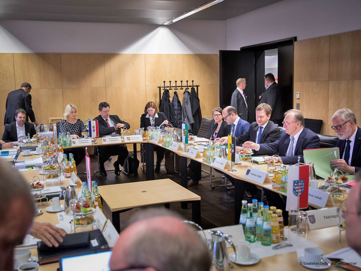 Männer und Frauen sitzen an einem Tisch und halten eine Konferenz.