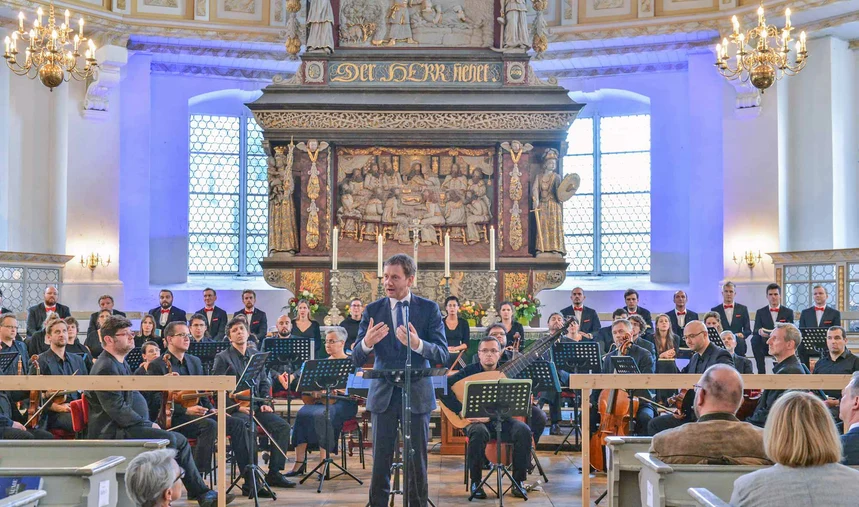 Ein Mann steht vor einem Orchester.