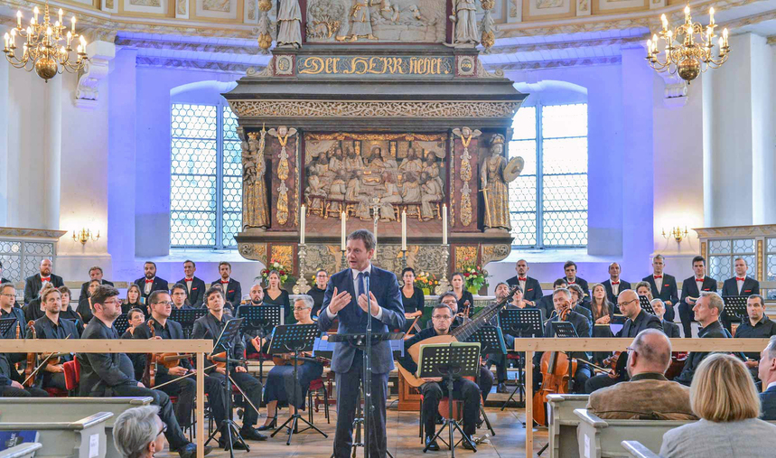 Ein Mann steht vor einem Orchester.