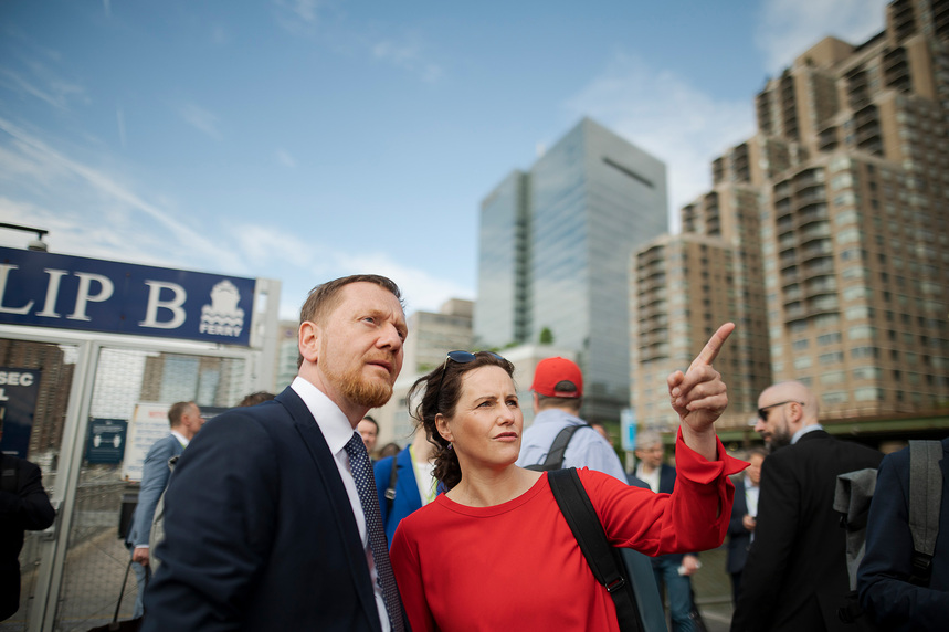 Ein Mann und eine Frau stehen vor Hochhäusern und blicken in die Ferne.