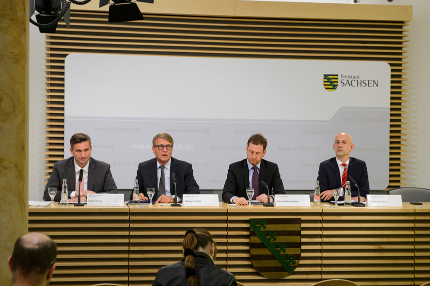 Männer sitzen auf einem Podium.