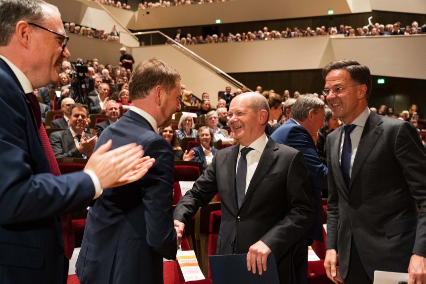 Zwei Männer reichen sich vor Publikum die Hand.