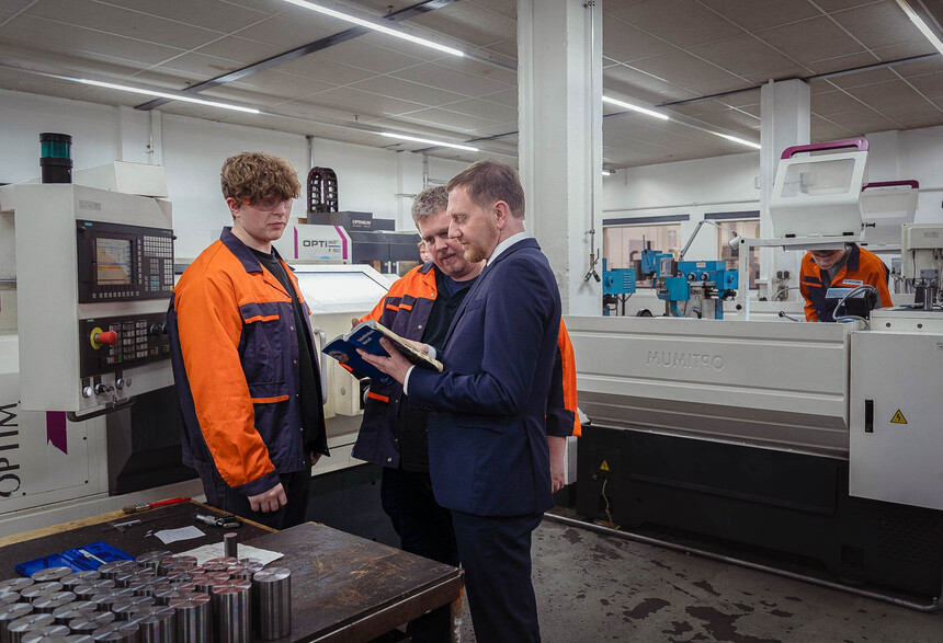 Männer unterhalten sich an einer Produktionsanlage.