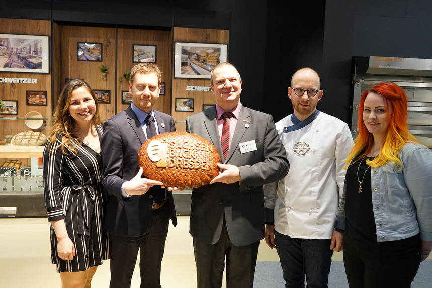 Männer und Frauen posieren mit einem Brot.