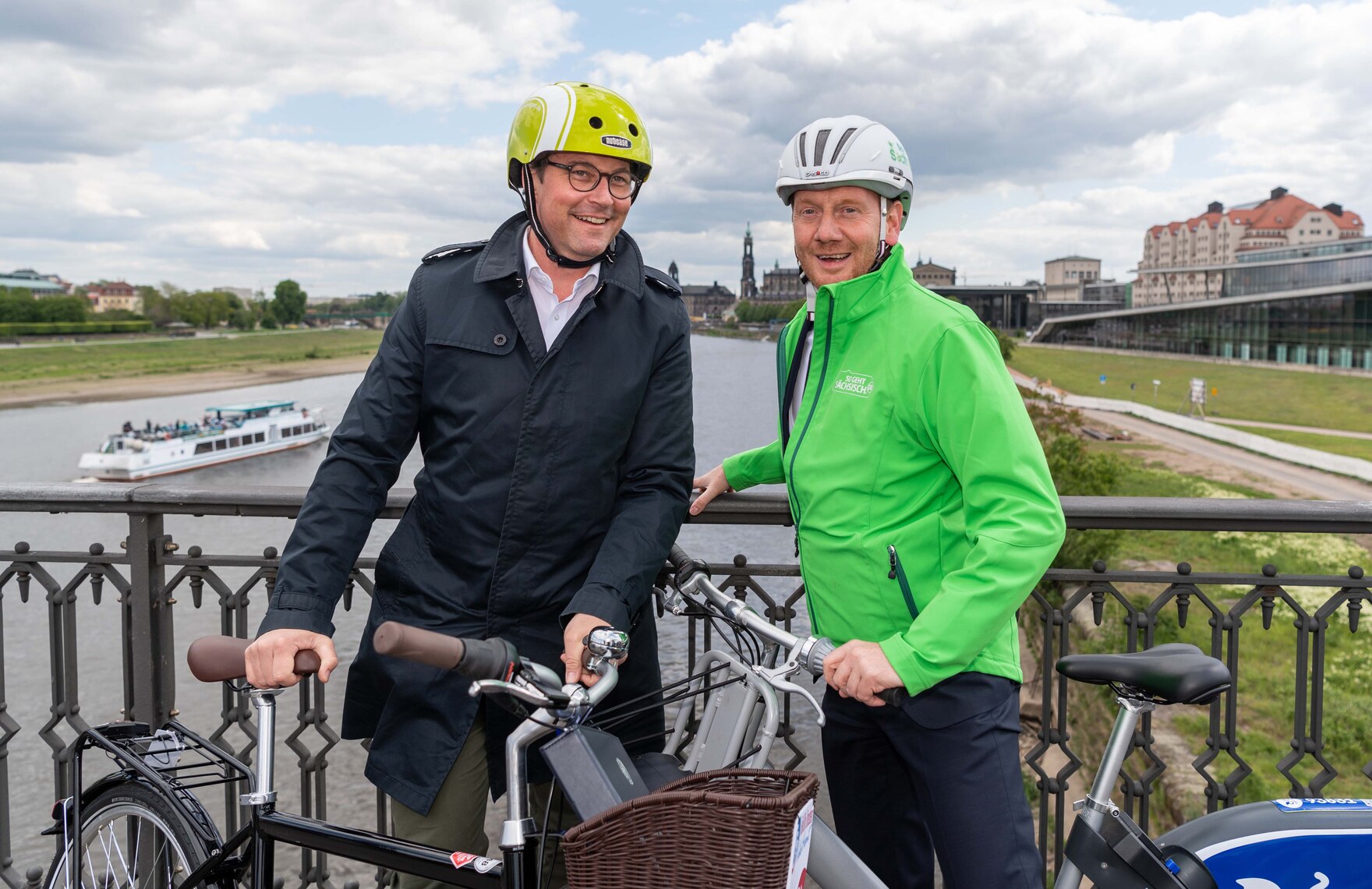 Zwei Männer stehen mit Fahrrädern auf einer Brücke.