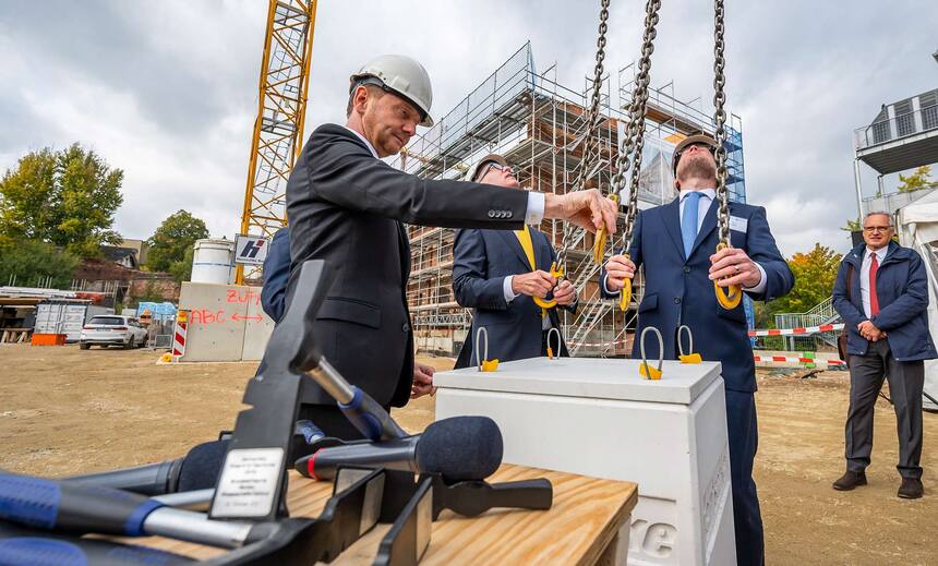 Männer stehen auf einer Baustelle vor einem Betonklotz.