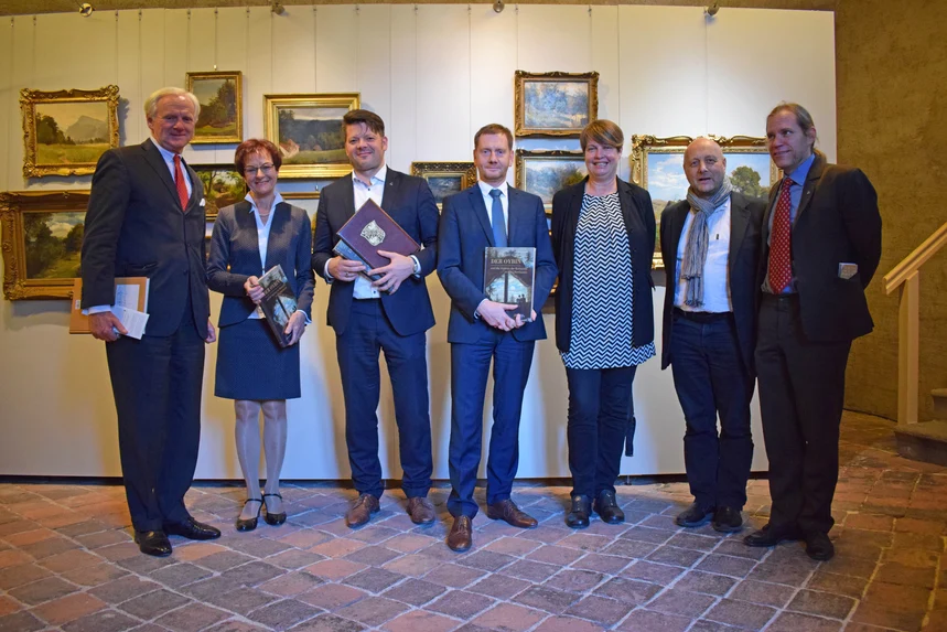 Männer und Frauen stehen vor einer Ausstellungswand.