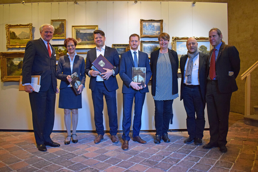 Männer und Frauen stehen vor einer Ausstellungswand.