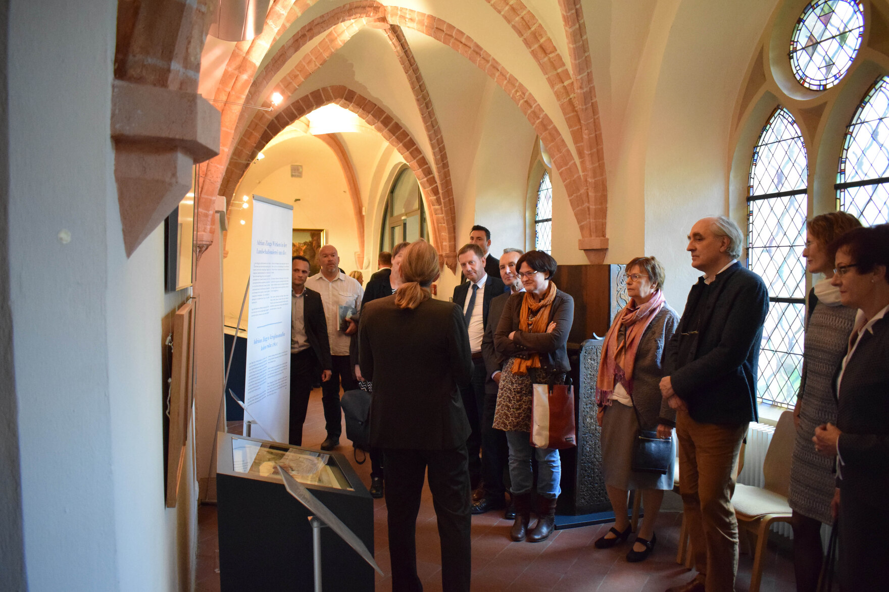 Männer und Frauen besuchen in einem alten Gemäuer eine Ausstellung.