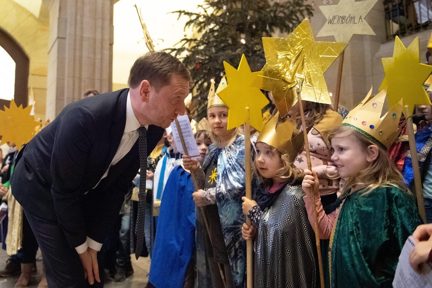 Ein Mann unterhält sich mit einem Kind, das als Sternsinger verkleidet ist.