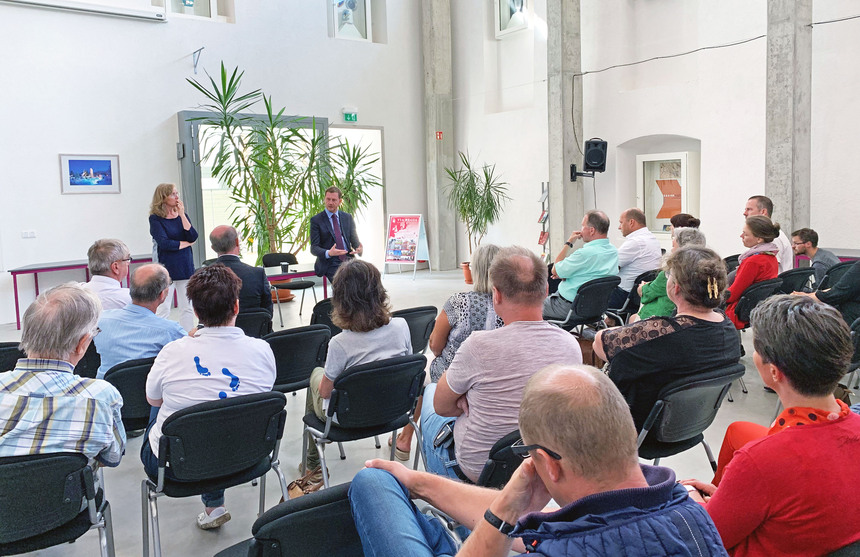 Ein Mann spricht vor einem versammlten Publikum in einem großen Saal.