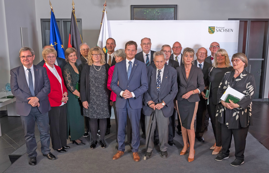 Männer und Frauen stehen in einer Gruppe für ein Foto zusammen.