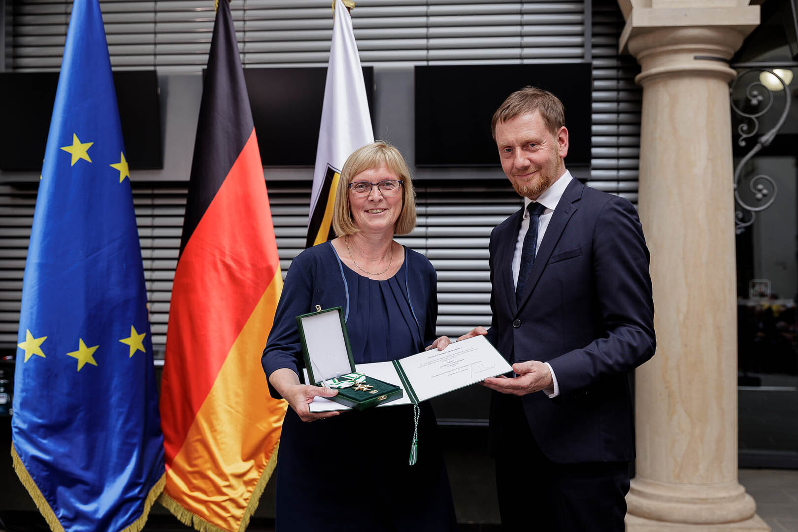 Ein Mann überreicht einer Frau einen Orden.