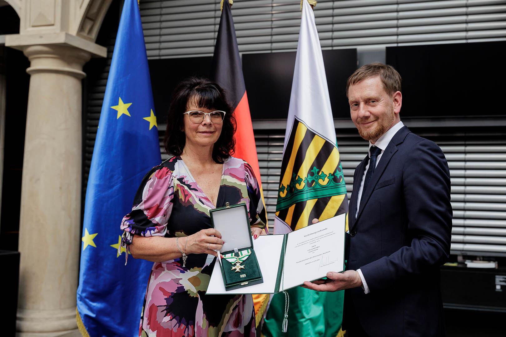 Ein Mann überreicht einer Frau einen Orden.
