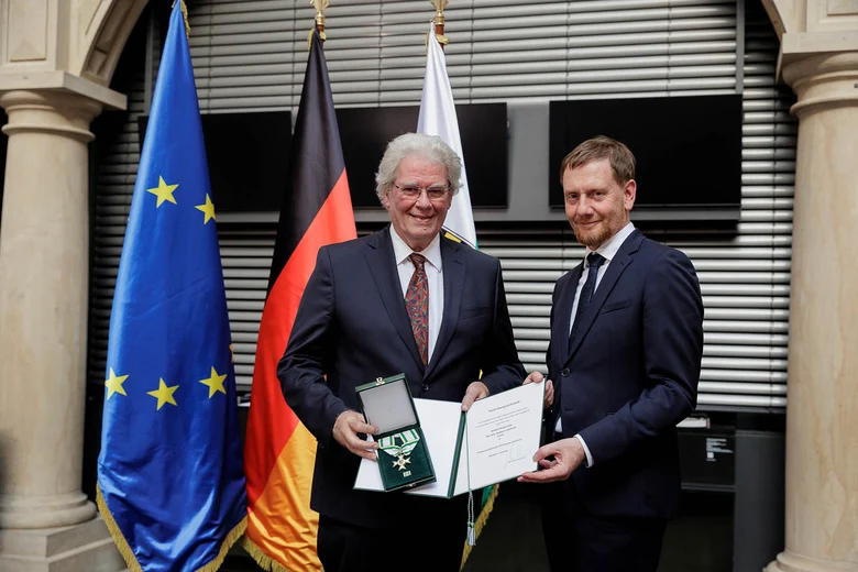Ein Mann überreicht einem Mann einen Orden.