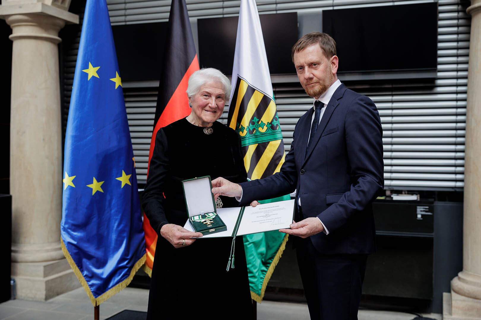 Ein Mann überreicht einer Frau einen Orden.
