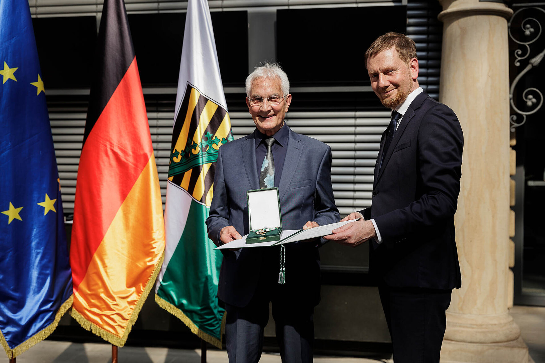 Ein Mann überreicht einem Mann einen Orden.
