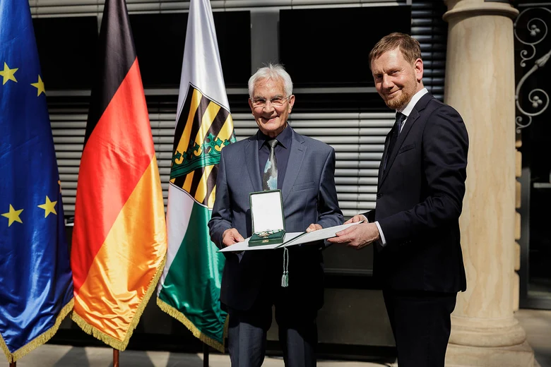Ein Mann überreicht einem Mann einen Orden.