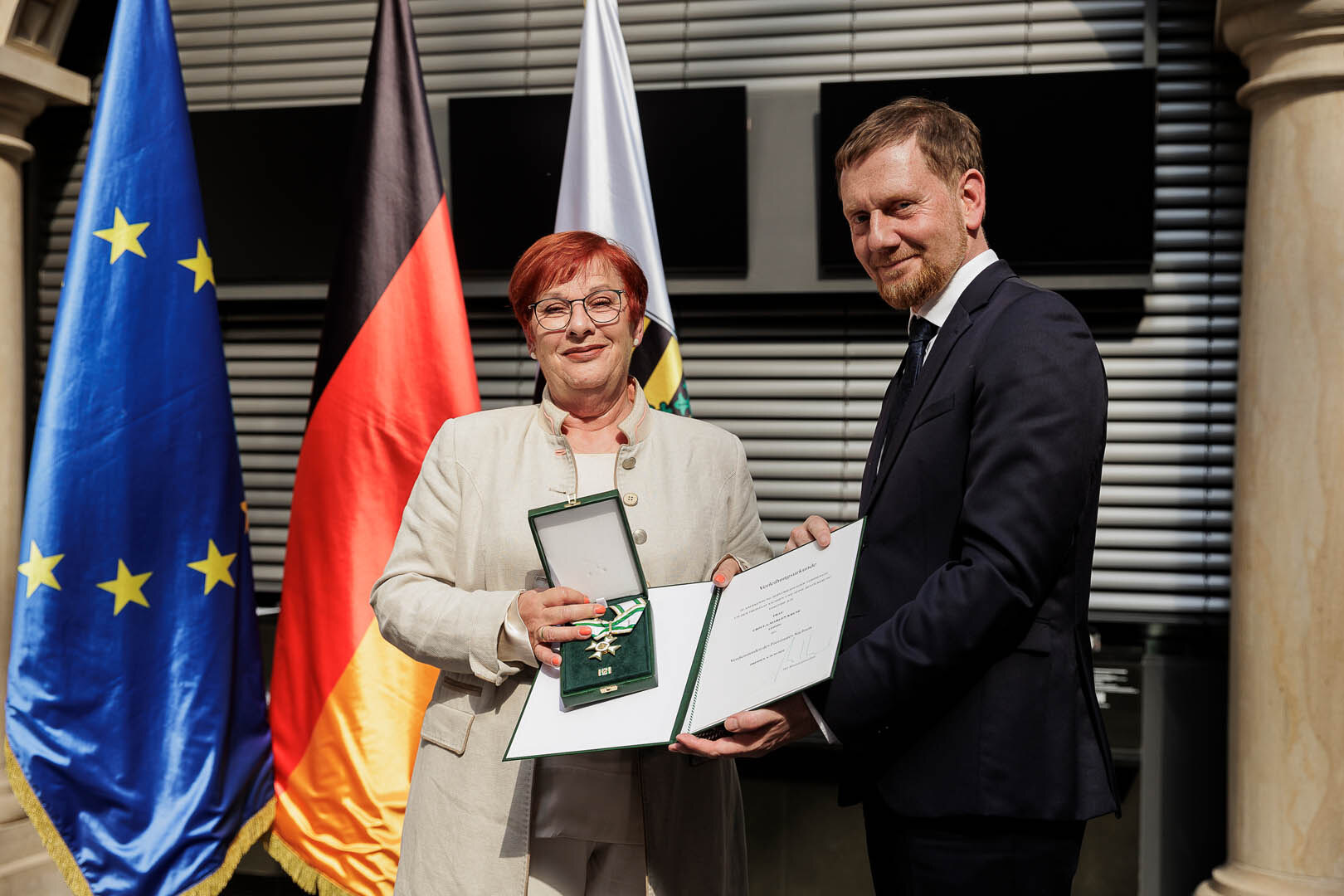 Ein Mann überreicht einer Frau einen Orden.