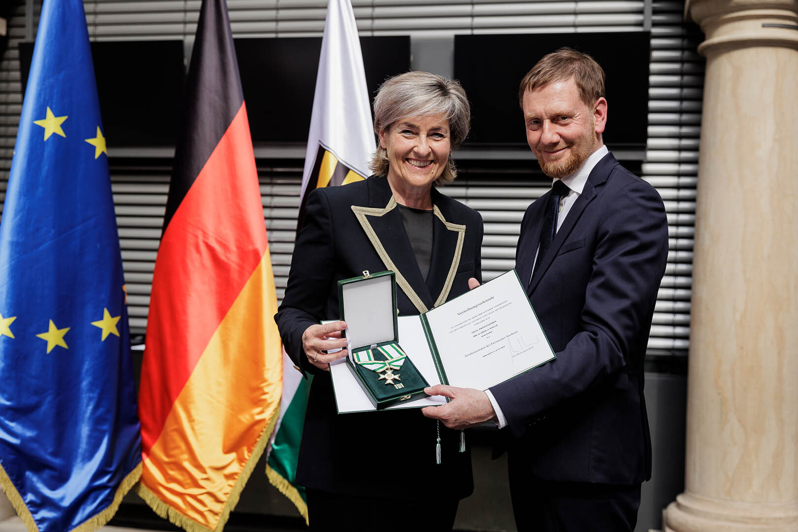 Ein Mann überreicht einer Frau einen Orden.