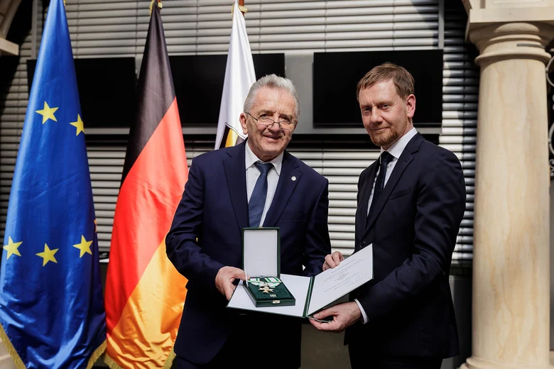 Ein Mann überreicht einem Mann einen Orden.
