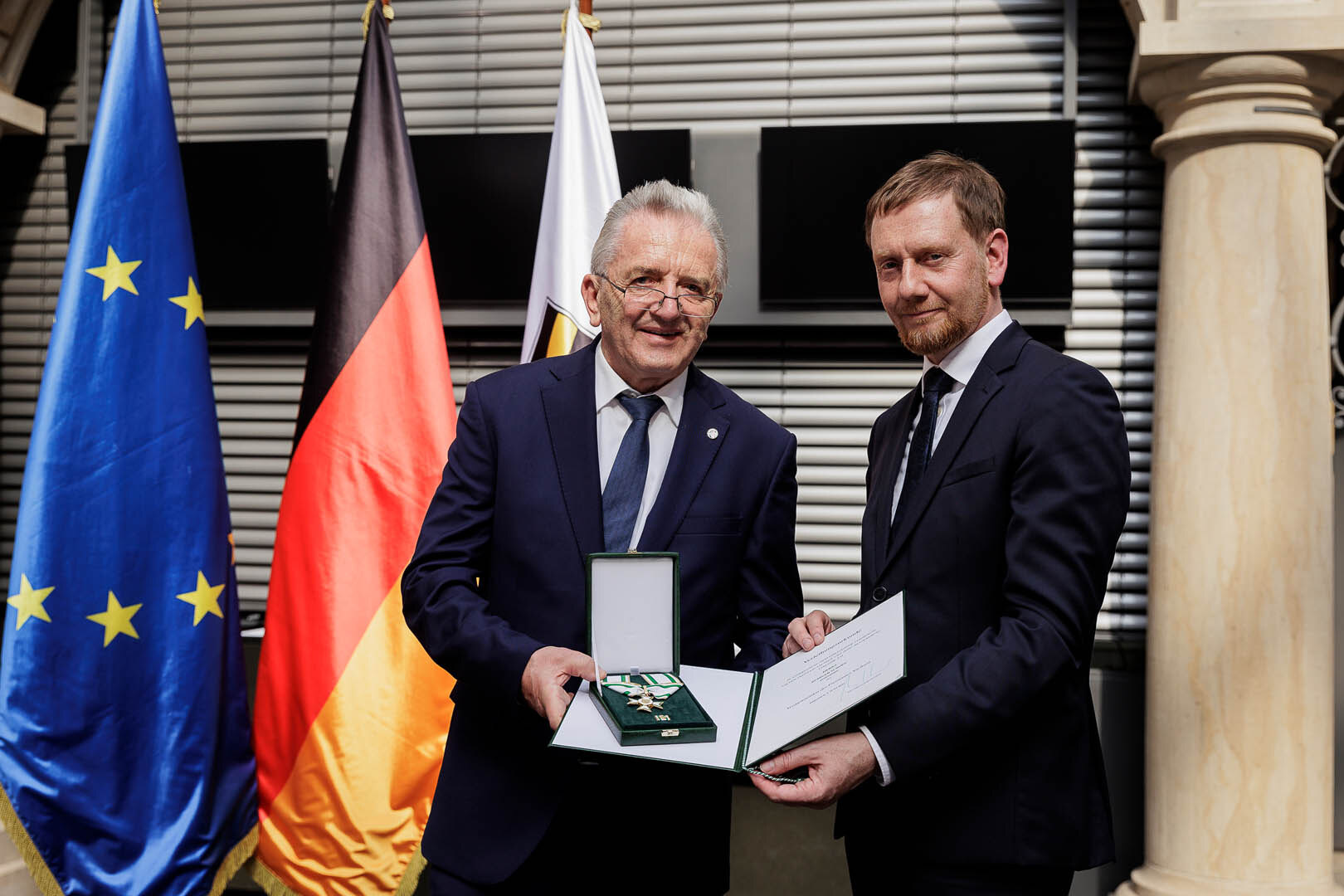 Ein Mann überreicht einem Mann einen Orden.