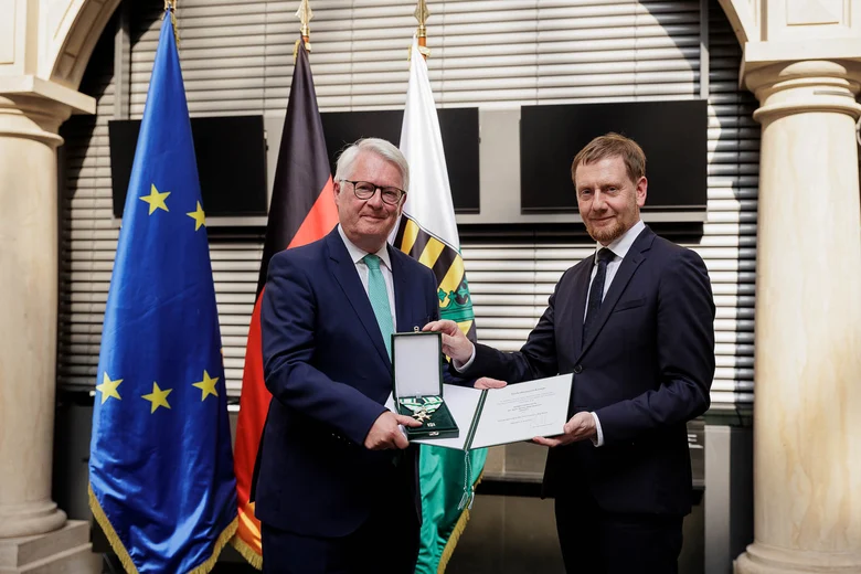 Ein Mann überreicht einem Mann einen Orden.