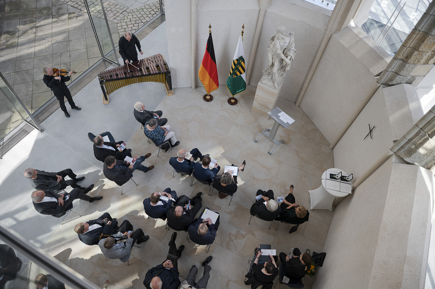 Männer und Frauen sitzen in einem kleinen Saal.