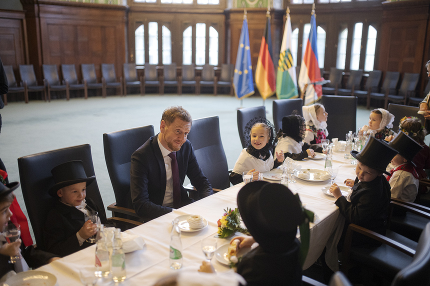 Ein Mann sitzt mit Kindern an einer Tafel.