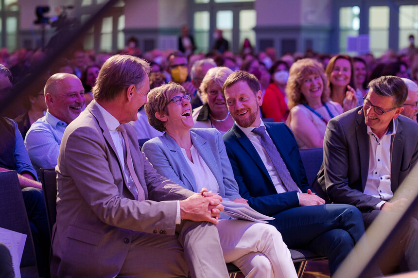 Männer und Frauen sitzen im Publikum.