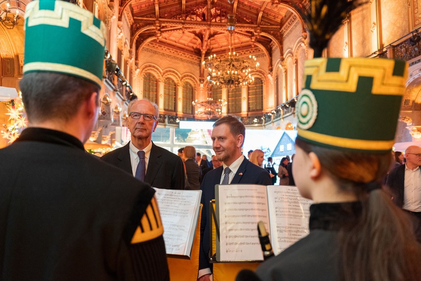 Zwei Männer stehen vor einer Gruppe Musikanten.