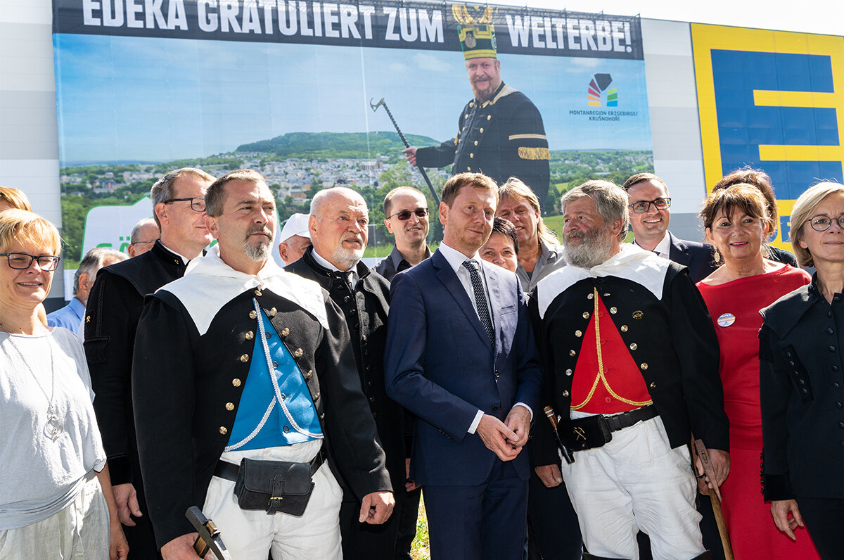 Männer und Frauen stehen vor einem riesigen Werbebanner.