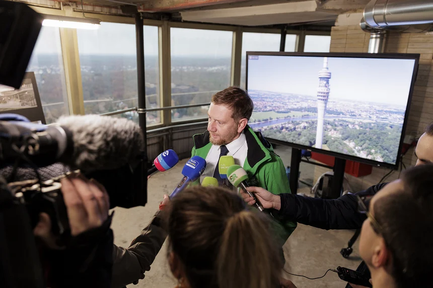 Ein Mann steht vor Menschen mit Mikrofonen in der Hand.