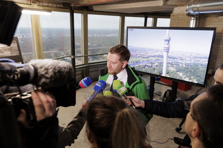 Ein Mann steht vor Menschen mit Mikrofonen in der Hand.