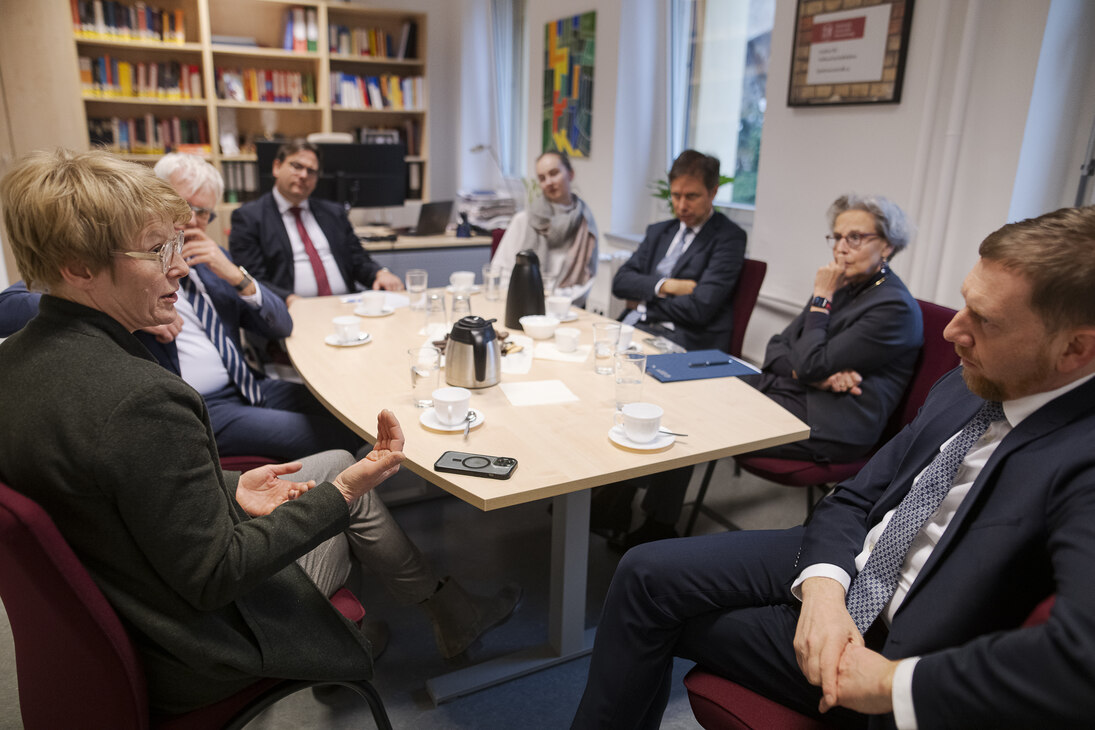 Männer und Frauen sitzen an einem Konferenztisch.