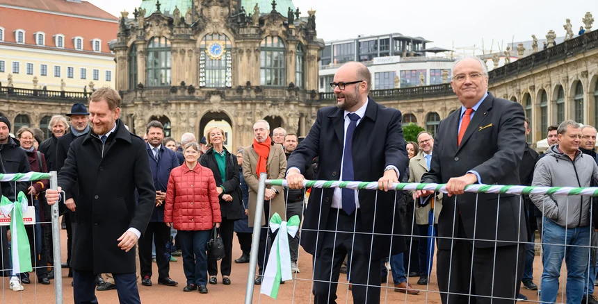 Drei Männer öffnen ein Tor.