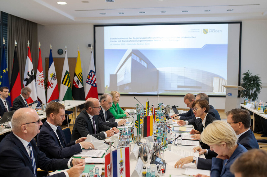 Männer und Frauen sitzen an einem Konferenztisch.