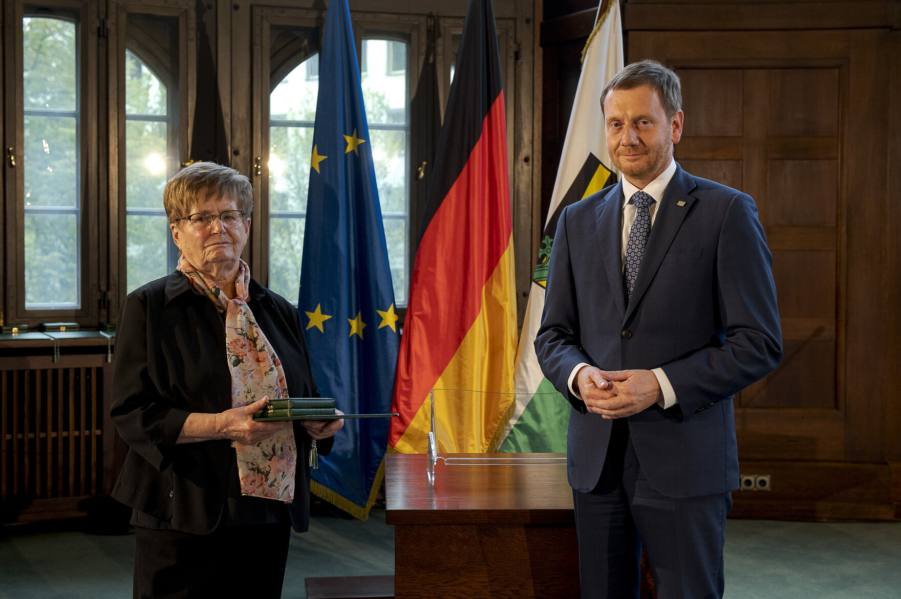 Ein Mann und eine Frauen stheen nebeneiander und halten einen Orden in der Hand.