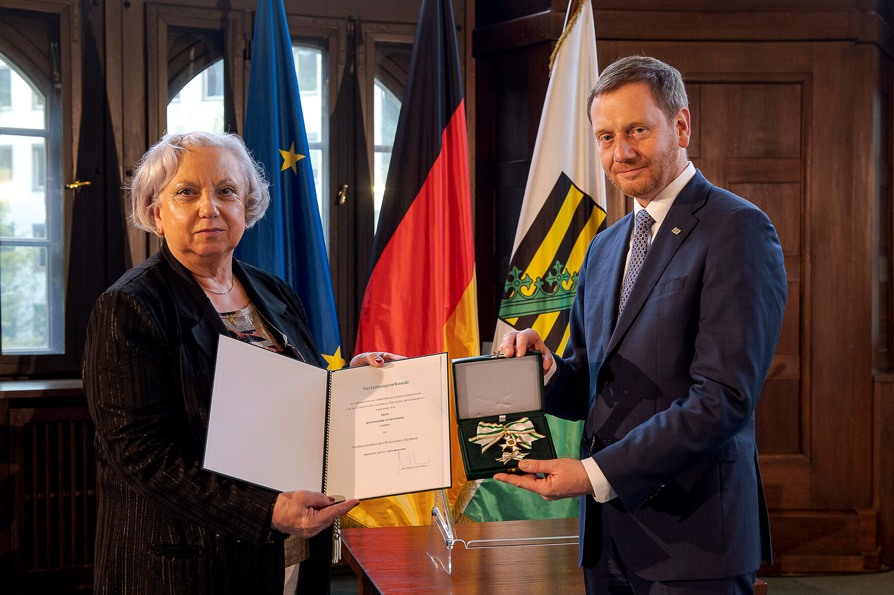 Ein Mann und eine Frau stehen nebeneinander und halten einen Orden in der Hand.