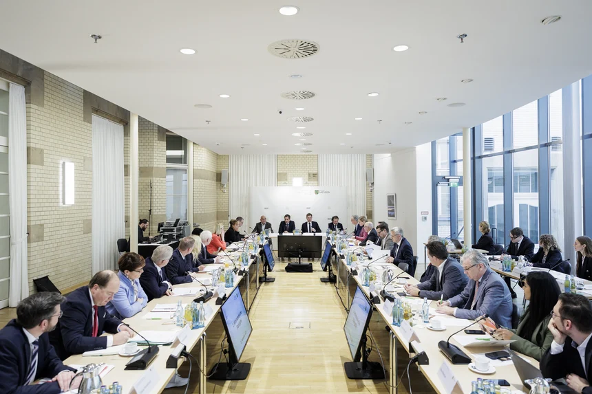 Männer und Frauen sitzen an einem Konferenztisch.