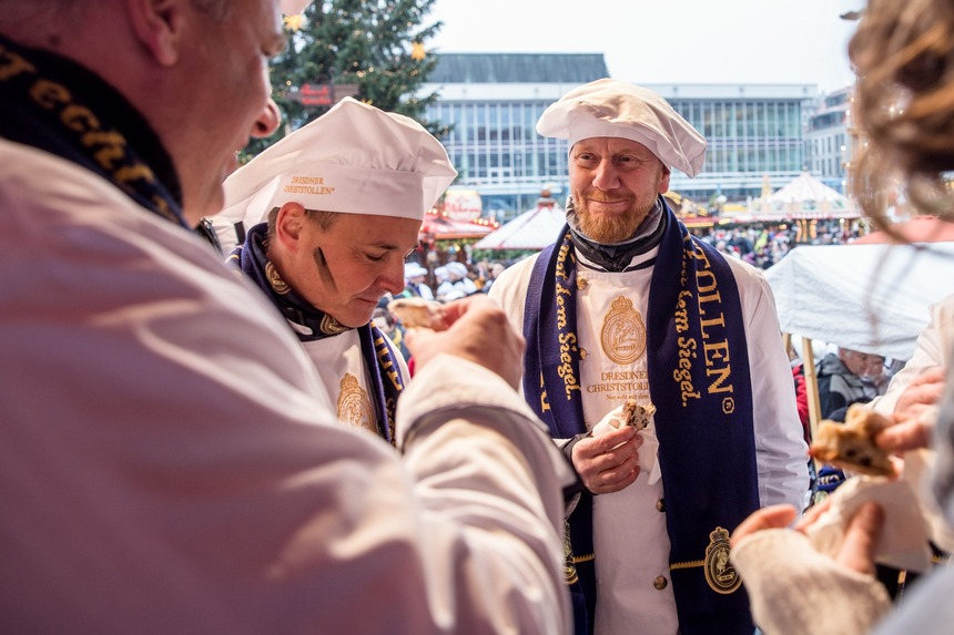 Männer in Bäckerkleidung essen Stollen.