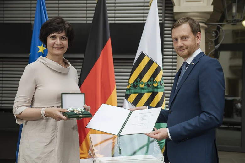 Eine Frau hält eine Urkunde in der Hand. Neben ihr steht ein Mann.