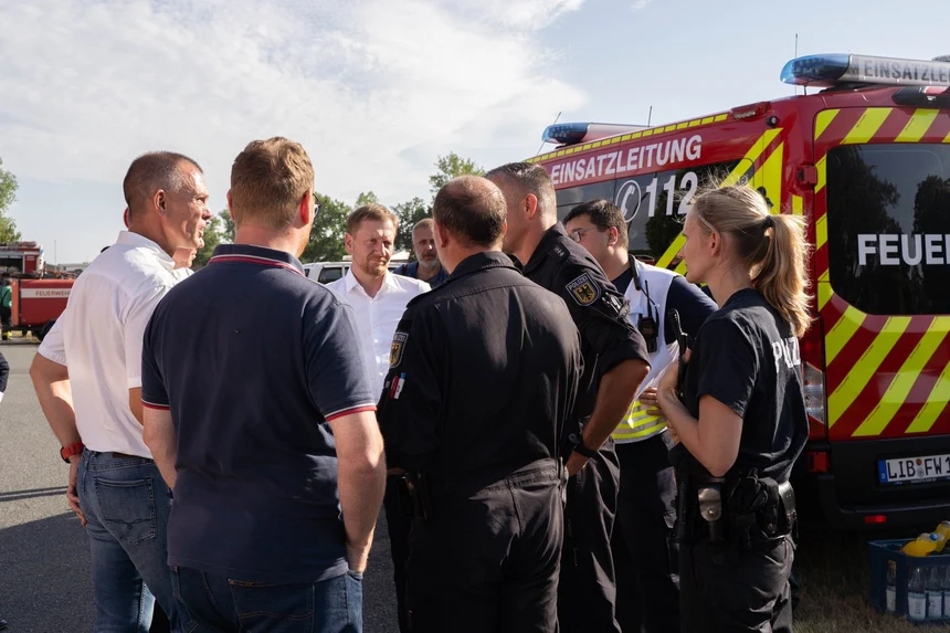 Männe rund Frauen stehen vor einem Feuerwehrauto.
