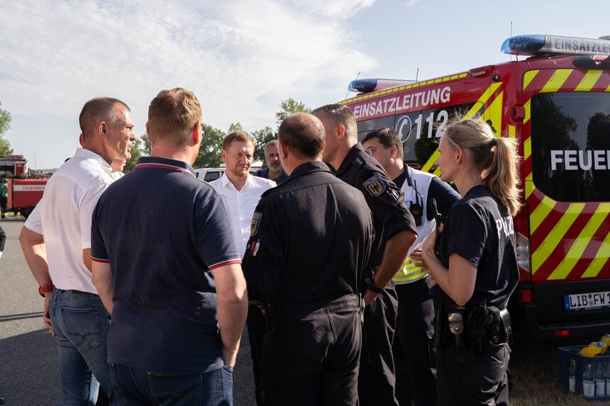 Männe rund Frauen stehen vor einem Feuerwehrauto.