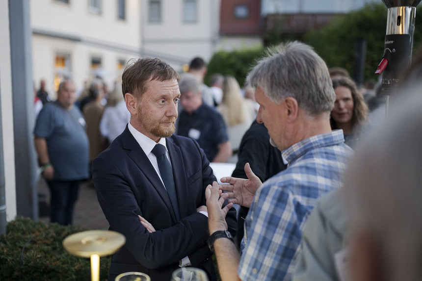 Zwei Männer unterhaltne sich an einem Stehtisch.