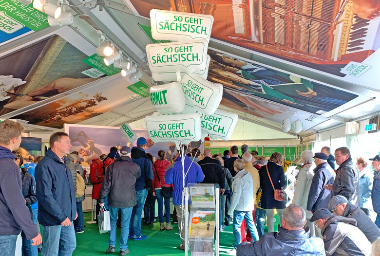 Männer und Frauen stehen in einem Zelt.