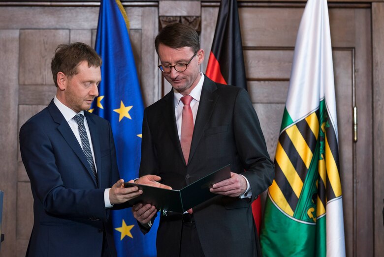 Ein Mann überreicht einem anderen Mann eine Urkunde.