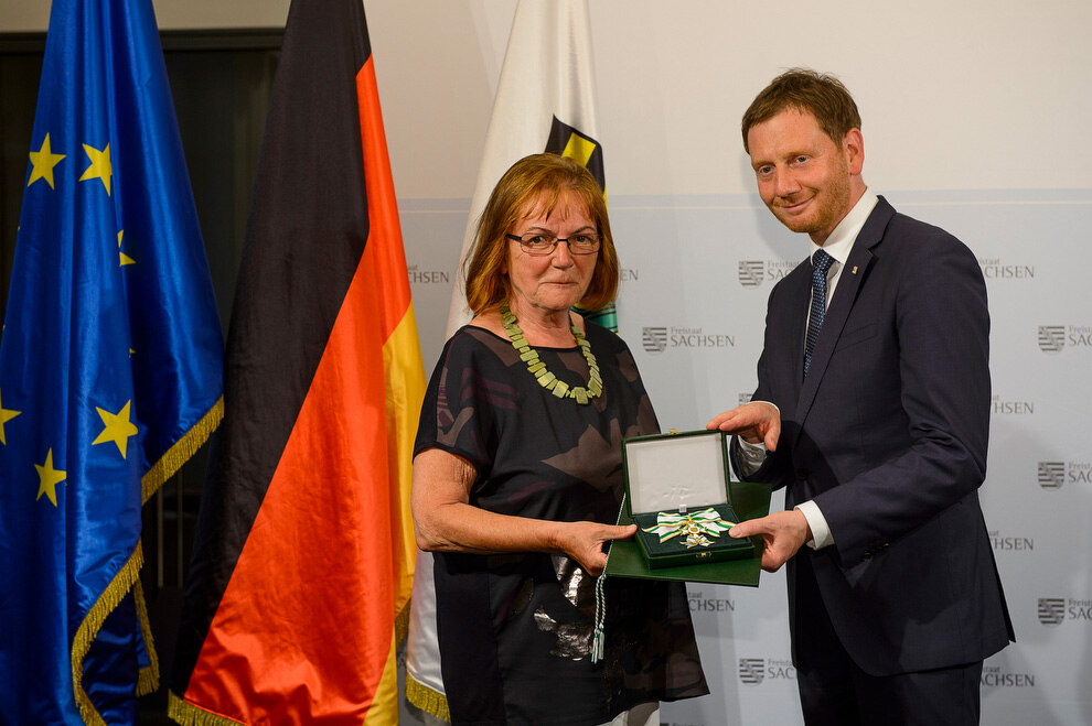 Ein Mann und eine Frau halten eine Medaille in der Hand.